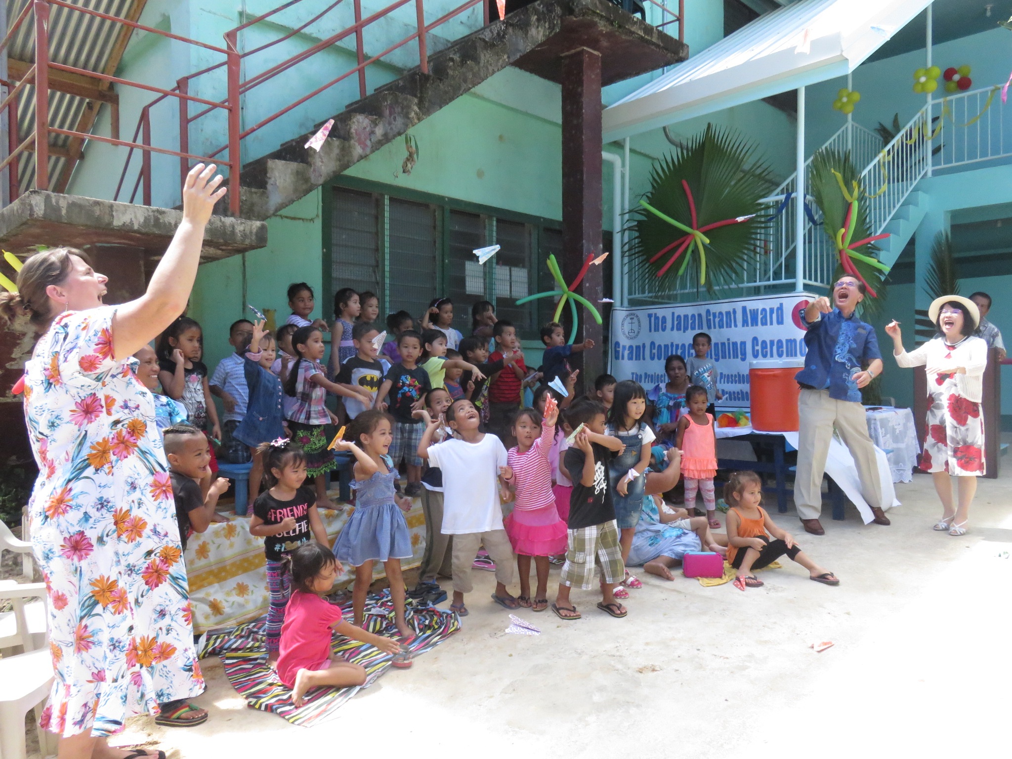Pupils happily throwing a paper plane which was a gift from Madam Horie.